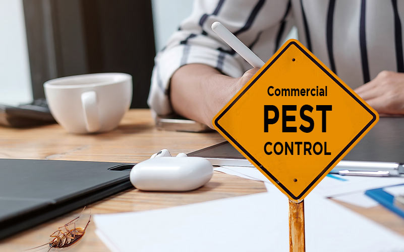 Background: Man working at desk. Foreground: Warning sign that reads "Commercial Pest Control"