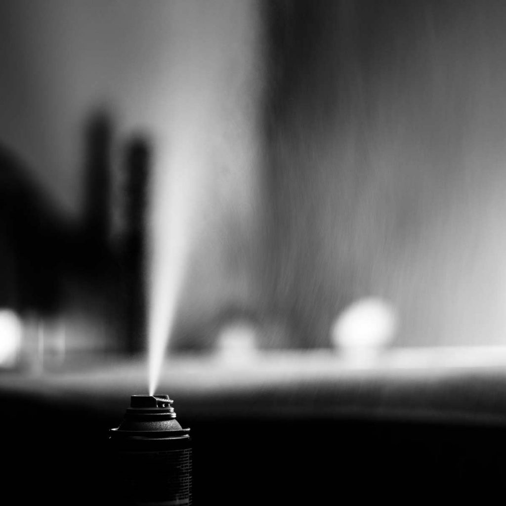 Black and white photo of a flea bomb (aka fogger) spraying chemical into the air